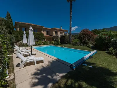 a swimming pool with two lawn chairs and an umbrella at Spacious Villa with Pool in Santʼ Andrea-dʼOrcino