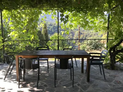 a wooden table and chairs on a patio at Maison de charme Corse sauvage in Pietra-di-Verde