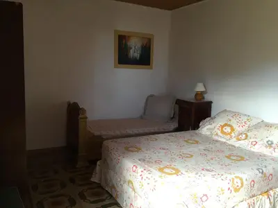 a bedroom with a bed and a chair in it at Maison de charme Corse sauvage in Pietra-di-Verde