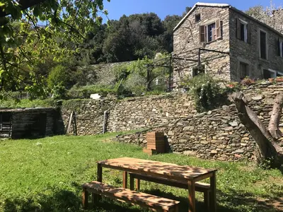 a wooden bench sitting in front of a stone building at Maison de charme Corse sauvage in Pietra-di-Verde