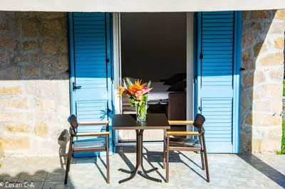 a table with two chairs and a vase with flowers on it at Résidence de Filitosa - Le Torréen in Sollacaro
