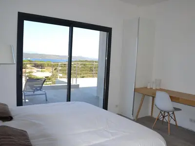 a bedroom with a bed and a desk and a balcony at Villas Pure Mare Bonifacio in Bonifacio