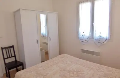 a bedroom with a bed and a chair and two windows at MORA in Conca