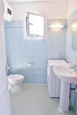a blue tiled bathroom with a toilet and a sink at MORA in Conca