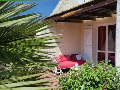 a red couch sitting on the porch of a house at Cosy Holiday Home in Cargèse Corse-du-Sud near Sea in Cargèse