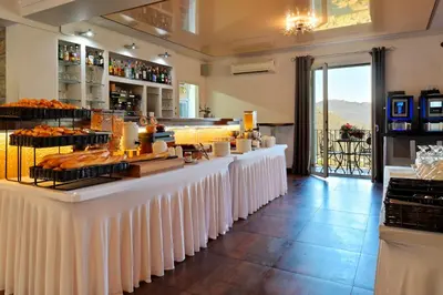 a bakery with a long counter with white tables at Hotel Des Roches in Sartène
