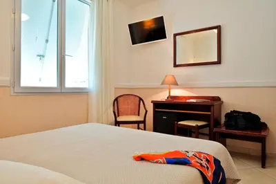 a bedroom with a bed and a desk and a mirror at Hotel Des Roches in Sartène