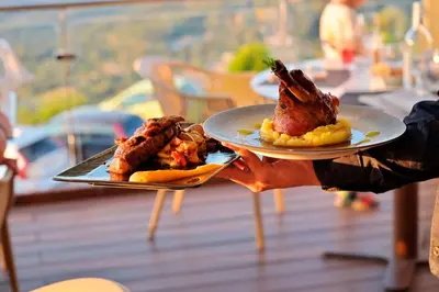 a person holding two plates with food on them at Hotel Des Roches in Sartène