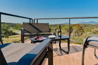 a patio with a table and a bottle of wine at Villa à l'entrée de Porticcio - Piscine - Vue dégagée in Cauro