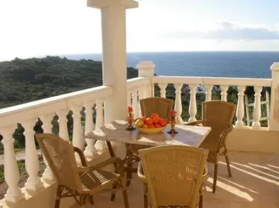 a table with chairs and a bowl of fruit on a balcony at Villa Liamone in Sagone