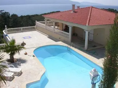 a large blue swimming pool in front of a house at Villa Liamone in Sagone