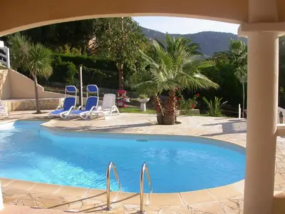 a swimming pool with blue chairs and palm trees at Villa Liamone in Sagone