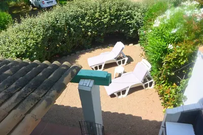 two white chairs and a bench on a patio at St CYPRIEN D23 in Porto-Vecchio