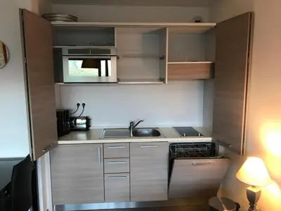a small kitchen with wooden cabinets and a sink at Studio standing Piscine vue mer in Porto-Vecchio