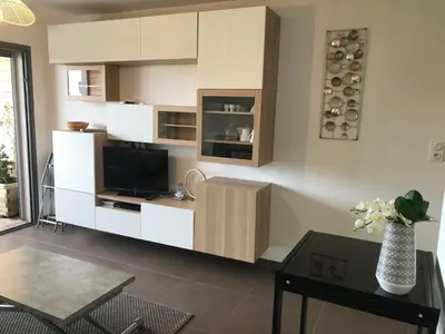 a living room with white cabinets and a television at Studio standing Piscine vue mer in Porto-Vecchio