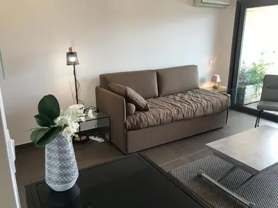 a living room with a couch and a vase with flowers at Studio standing Piscine vue mer in Porto-Vecchio