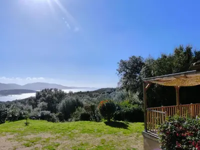 a house with a balcony with a view of the ocean at Magnifique chalet vue mer, a quelques minutes des plages in Olmeto