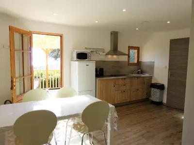 a kitchen with a white table and chairs in it at Magnifique chalet vue mer, a quelques minutes des plages in Olmeto