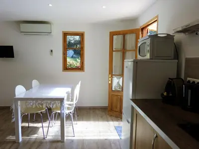 a kitchen with a table with chairs and a refrigerator at Magnifique chalet vue mer, a quelques minutes des plages in Olmeto