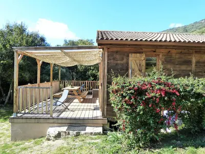 a wooden gazebo with a chair on a deck at Magnifique chalet vue mer, a quelques minutes des plages in Olmeto