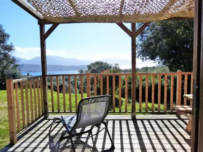 a chair sitting on a deck with a fence at Magnifique chalet vue mer, a quelques minutes des plages in Olmeto