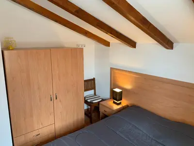 a bedroom with a bed and a cabinet and a chair at Les pieds dans l'eau en Corse ! in Moriani Plage