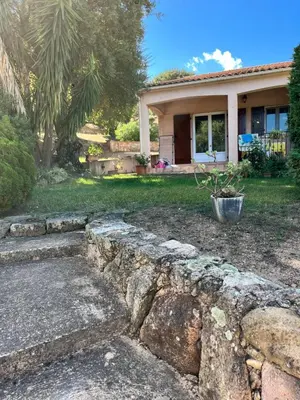 a house with a stone wall in front of a yard at residence Catalani in Zonza