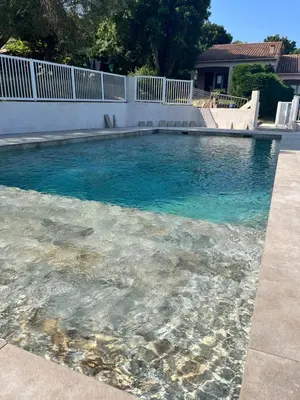 a swimming pool with blue water and a white fence at residence Catalani in Zonza