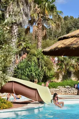a girl in a swimming pool with a slide at Les Suites De Pertamina in Bonifacio