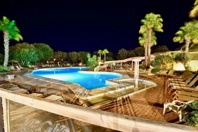 a swimming pool in a resort at night at Les Suites De Pertamina in Bonifacio