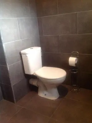 a bathroom with a white toilet in a tiled wall at charmant studio dans résidence neuve et calme in Corte