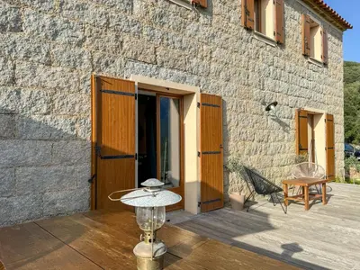 a stone building with a wooden door and a patio at Maison de campagne, deux chambres, vue sur les montagnes in Sartène