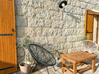 a table and a chair next to a brick wall at Maison de campagne, deux chambres, vue sur les montagnes in Sartène