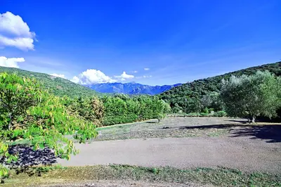 a dirt road with trees and mountains in the background at Orasi, Sartene, gîte dans villa climatisée tout confort in Sartène