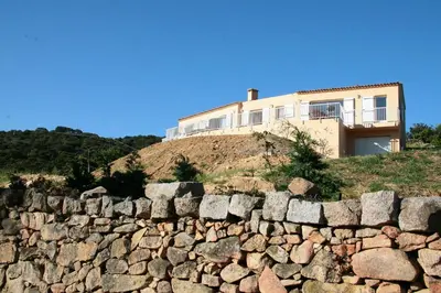 a house on top of a hill with a stone wall at Orasi, Sartene, gîte dans villa climatisée tout confort in Sartène