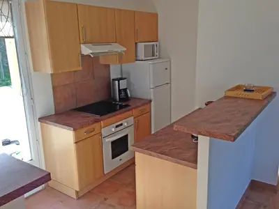 a small kitchen with wooden cabinets and a white refrigerator at Orasi, Sartene, gîte dans villa climatisée tout confort in Sartène