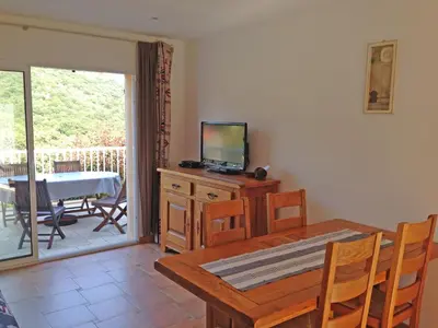 a dining room with a table and a television on a cabinet at Orasi, Sartene, gîte dans villa climatisée tout confort in Sartène
