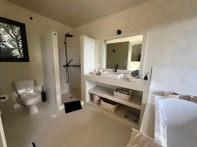 a bathroom with a sink and a toilet and a mirror at Villa Valrossa in Porto-Vecchio