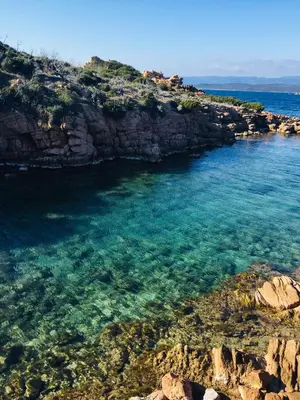a large body of water with a rocky shore at A GIOIA DI CAMPA in Figari