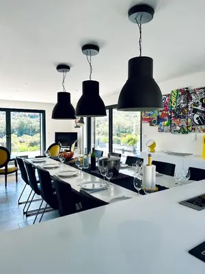 a dining room with a long table and black pendant lights at A GIOIA DI CAMPA in Figari