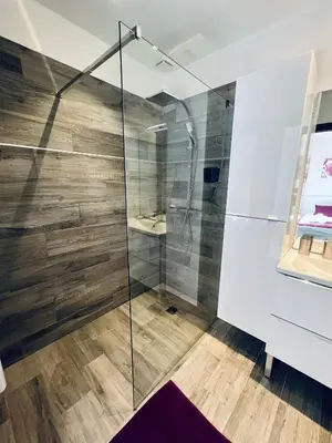 a glass shower in a bathroom with wooden floors at A GIOIA DI CAMPA in Figari