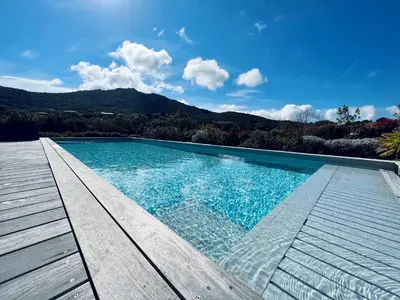 a swimming pool with a wooden deck next to at A GIOIA DI CAMPA in Figari