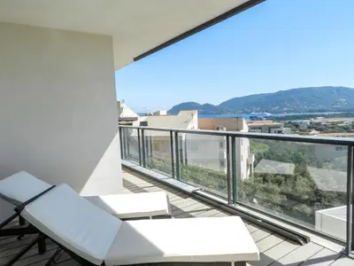 a balcony with white furniture and a view of the city at Apartment Château-5 by Interhome in Porto-Vecchio
