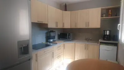 a kitchen with white cabinets and a wooden table at Joli villa Marcel classée 3 étoiles in Calenzana