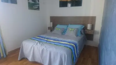 a bedroom with a bed with blue sheets and green pillows at Joli villa Marcel classée 3 étoiles in Calenzana