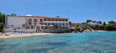 a building on the shore of a body of water at Hôtel U Paradisu in Porticcio