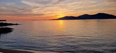 a sunset over a body of water with a mountain at Hôtel U Paradisu in Porticcio