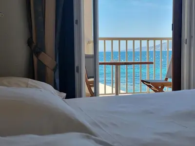 a bedroom with a bed and a view of the ocean at Hôtel U Paradisu in Porticcio