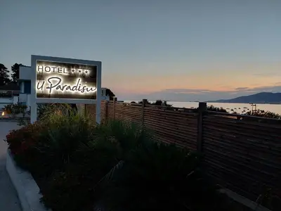 a sign for a hotel next to a fence at Hôtel U Paradisu in Porticcio