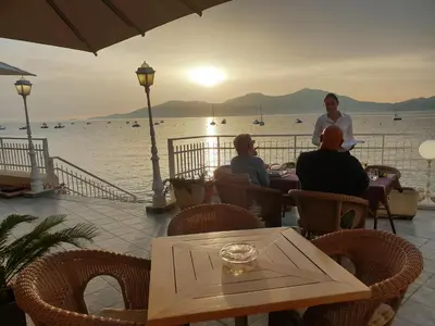 a group of people sitting at a table near the water at Hôtel U Paradisu in Porticcio
